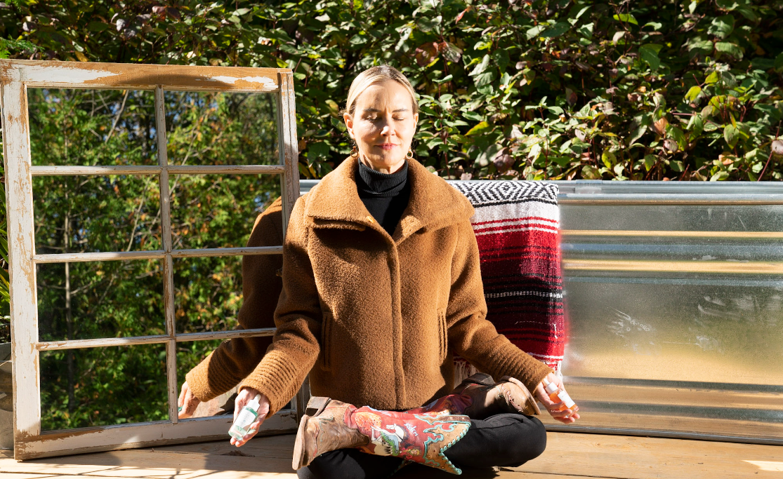 Graydon Moffat, meditating outdoors while holding a bottle of Graydon Skincare Fullmoon Serum and Graydon Skincare Moon Boost Serum.u