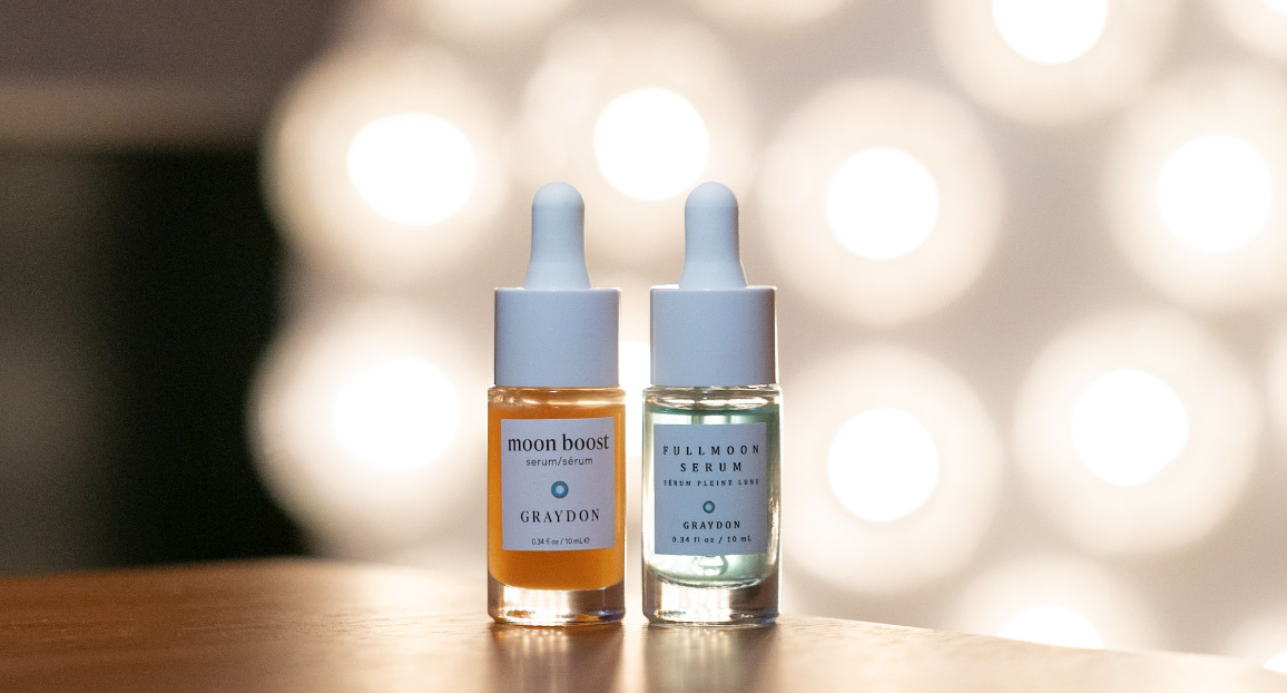 10 mL bottles of Graydon Skincare Moon Boost Serum and Fullmoon Serum with bright lights behind.