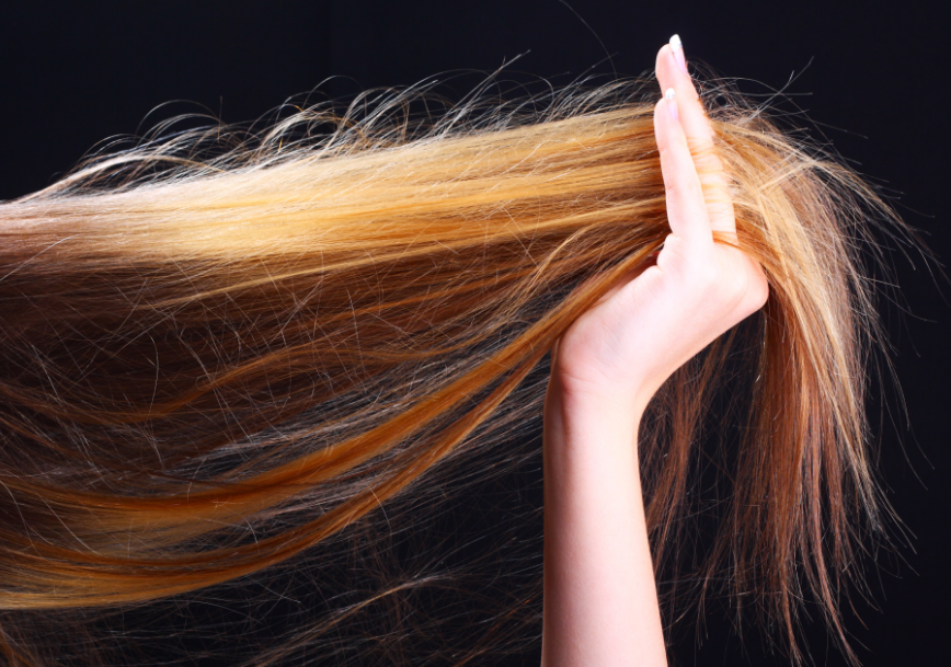 Woman's hand holding length of hair on black background