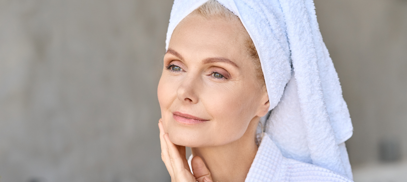Older woman in a robe touching her face